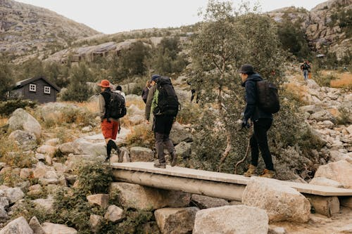 Hikers crossing a wooden bridge with backpacks on a rocky trail.