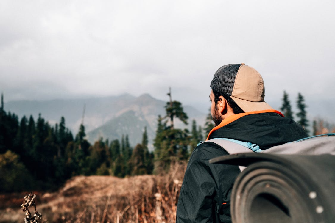 Hiker wearing a backpack looking out over a mountain landscape.