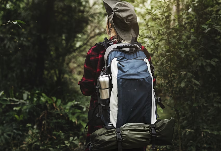  A photo of a woman with a backpack in a forest. 