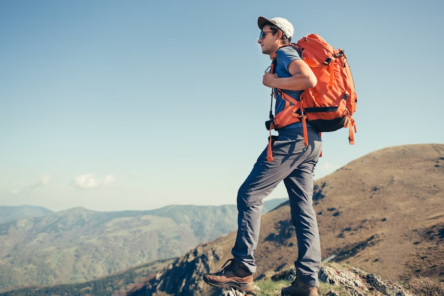 A photo of a hiker with an orange backpack..