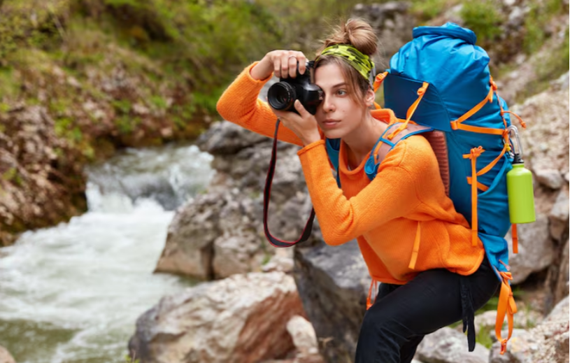 Outdoor photographer hiking with a camera backpack while capturing scenic mountain landscapes