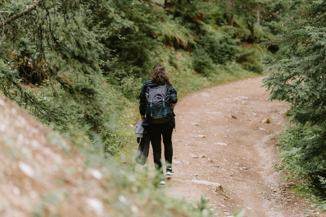 Woman hiking alone on a forest trail carrying a backpack.