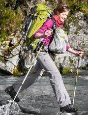picture of woman hiker crossing stream wearing Aarn hiking backpack